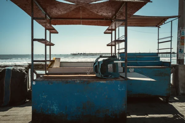 Rustic abandoned stalls on a deserted beach with ocean view, capturing solitude and decay.