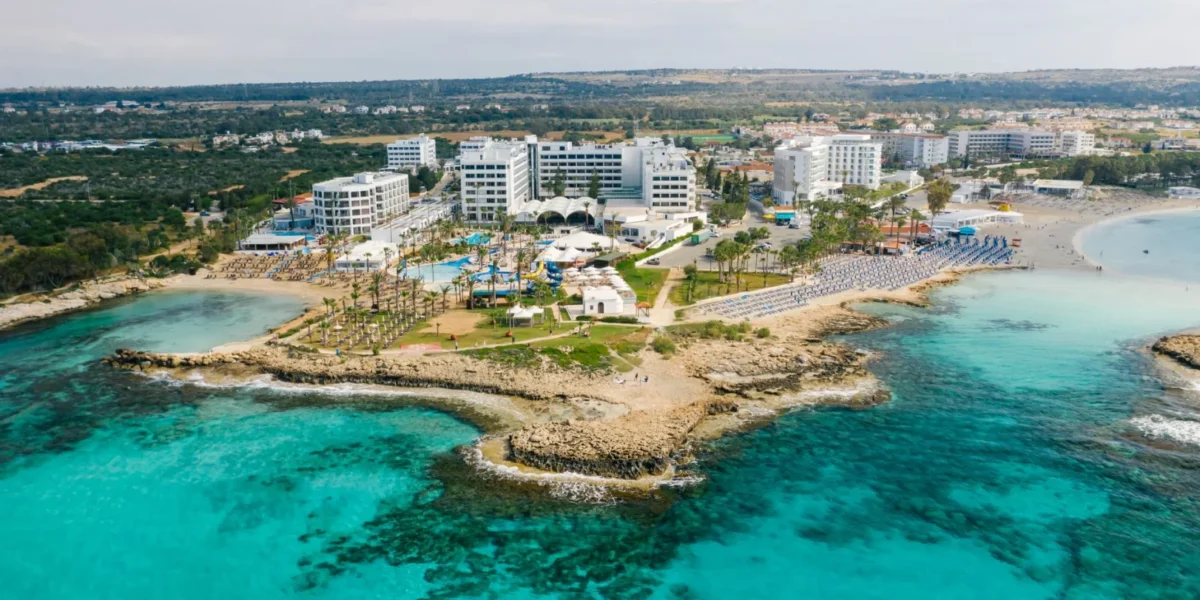Stunning aerial shot of a Cyprus seaside resort showcasing crystal clear waters and luxury hotels.