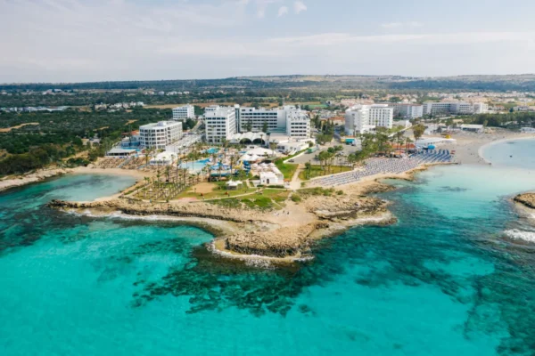 Stunning aerial shot of a Cyprus seaside resort showcasing crystal clear waters and luxury hotels.