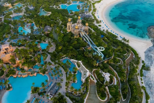 Explore the stunning aerial shot of a tropical beach resort featuring lush green trees and turquoise swimming pools.