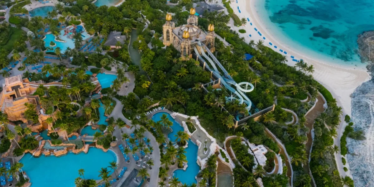 Explore the stunning aerial shot of a tropical beach resort featuring lush green trees and turquoise swimming pools.