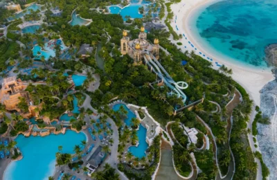 Explore the stunning aerial shot of a tropical beach resort featuring lush green trees and turquoise swimming pools.